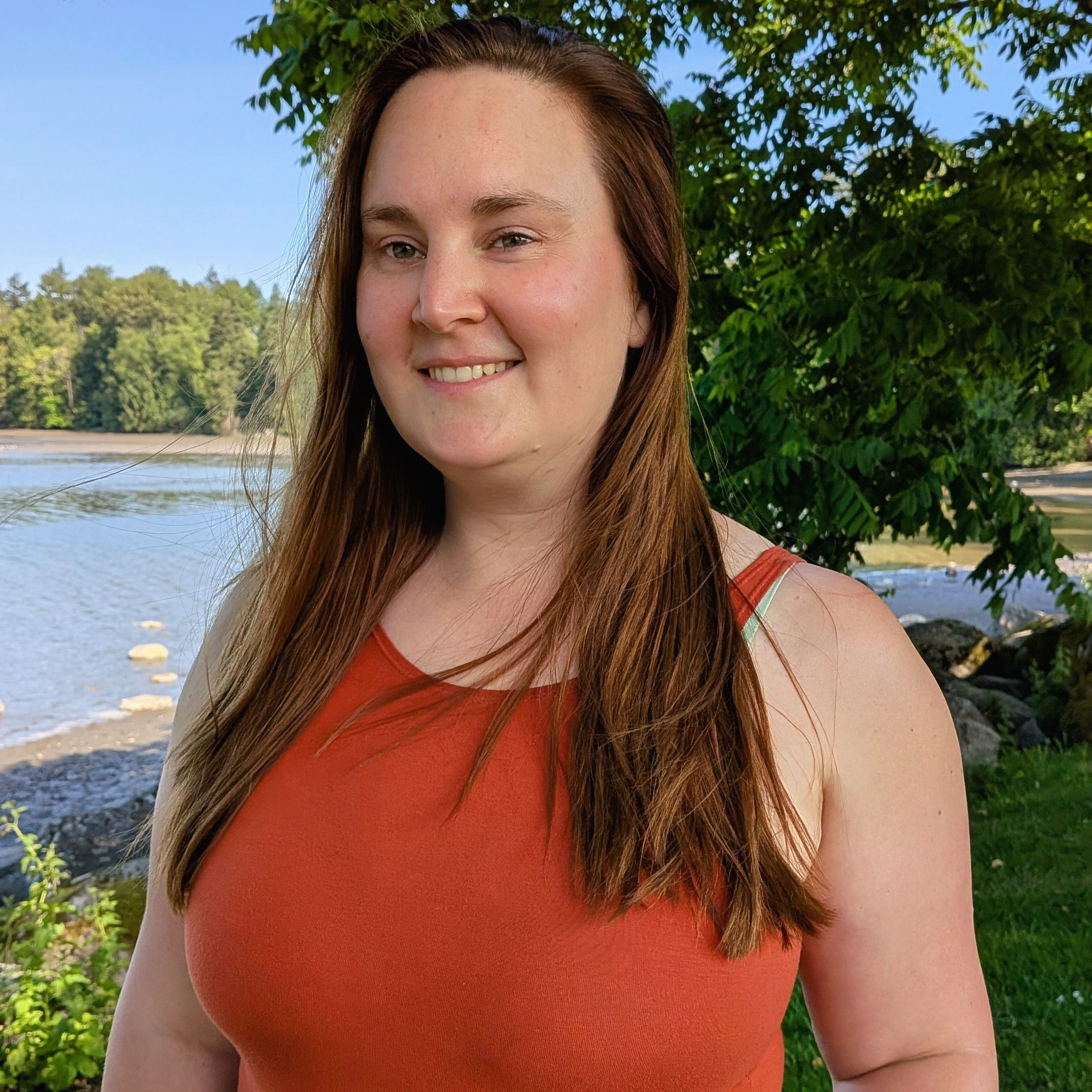 Jeanine Longley at Rocky Point Park, wearing an orange shirt, hair blowing slightly in the wind, looking to the left of the camera somewhat.